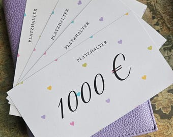 May include: A stack of white rectangular gift cards featuring the text PLATZHALTER and 1000 € in black font, decorated with small multicoloured hearts. The cards are fanned out and placed on top of a textured light purple leather-like cover.