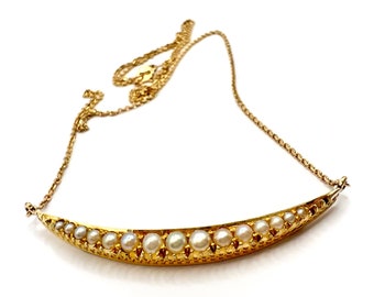 Op de afbeelding: Een gouden ketting met een halve maanvormige hanger bezet met parels.