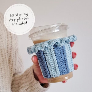 May include: A light blue and dark blue striped crochet cup sleeve with a ruffled top edge, wrapped around a clear plastic cup containing a tan liquid. A circular white graphic overlay displays the text 38 step by step photos included.