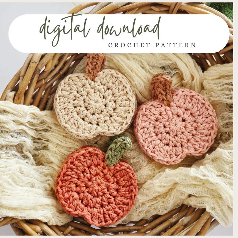 May include: Three crocheted pumpkin-shaped coasters in a woven basket. The coasters are in beige, peach, and orange, with brown and green stems. The image includes the text "digital download" and "crochet pattern".