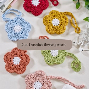 May include: Six crocheted flower shapes in different colours, including red, blue, yellow, green, orange, and pink. Each flower has a white centre and a crocheted loop for hanging. The flowers are arranged on a white surface with the text "6 in 1 crochet flower pattern."