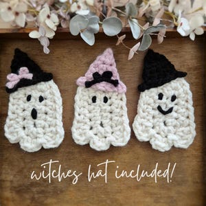 May include: Three handmade crochet ghosts with black and pink witch hats. Each ghost has a unique facial expression, with button eyes and a stitched mouth. The text "witches hat included!" is written in a cursive font.