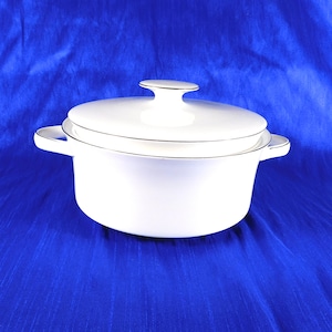 May include: A white ceramic casserole dish with a matching lid and two side handles. The dish features a smooth, glossy finish with a thin silver metallic trim along the edges of the lid, the rim of the pot, and the outer edges of the handles.