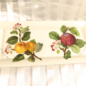 Puede incluir: Bandeja rectangular crema con ilustraciones botánicas. Presenta manzanas y ramas con hojas verdes y flores rosas y blancas. Las manzanas son amarillas y rojas.