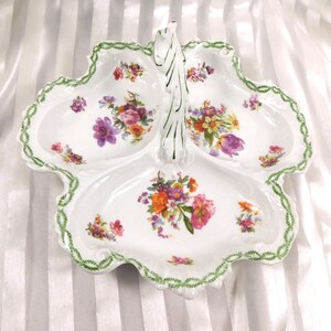 Könnte beinhalten: Weißes Porzellan-Serviertablett mit drei Fächern und einem Griff. Das Tablett ist mit bunten Blumensträußen und einem grünen, blattartigen Rand verziert. Der Griff hat ein dekoratives, blattartiges Design.