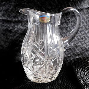 May include: A clear glass pitcher with a cut crystal design. The pitcher has a handle and a label that reads "Lead Crystal."