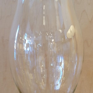 以下が含まれることがあります： 幅広で丸みを帯びたボディとフレアトップを備えた、透明なガラス製のハリケーンキャンドルホルダー。 ガラスは滑らかで透明で、光と周囲の環境を反射します。 ベースもフレアです。