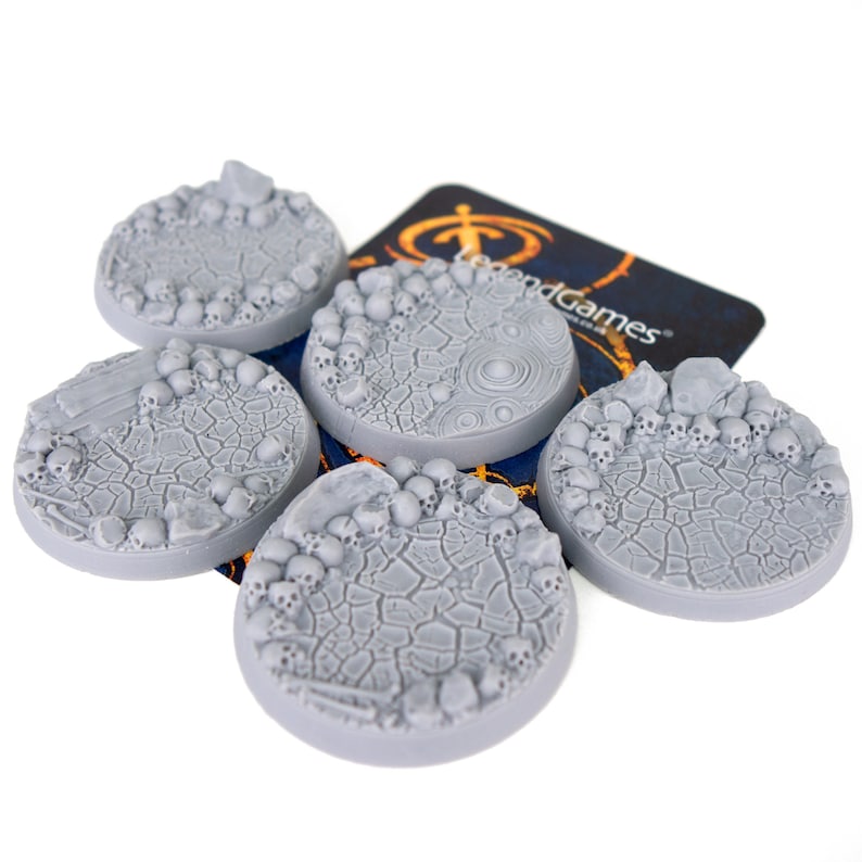 May include: Six grey plastic miniature bases with a skull and bone design. The bases are for use in tabletop games.