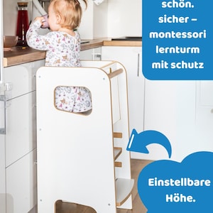May include: A white wooden learning tower with a safety rail and adjustable height platform. The structure features side cutouts and natural wood accents. Text on the image reads: Stabil. sch&ouml;n. sicher - montessori lernturm mit schutz, Einstellbare H&ouml;he. Max. 50 kg.