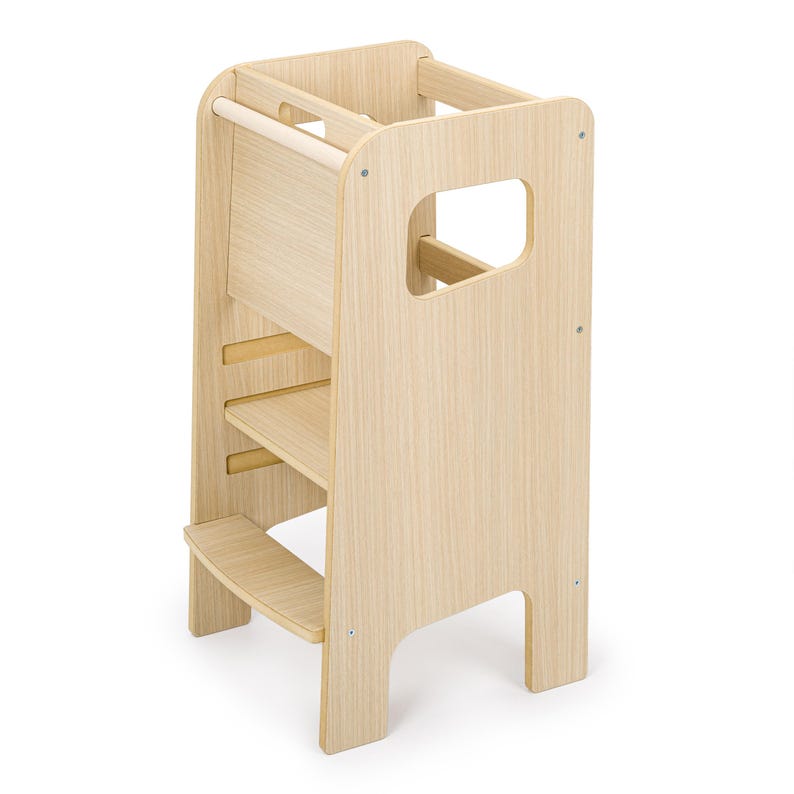 May include: A light-coloured wooden learning tower featuring a tall, open-frame design with a sturdy base, a middle platform, and a top safety rail. The structure includes side cutouts for handles and is constructed from smooth, light-toned wood panels.