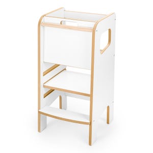 May include: A white wooden learning tower with natural light wood edges. This structure features a tall safety enclosure, a sturdy standing platform, and a lower step for access. The side panels include cut-out handles for portability and stability.
