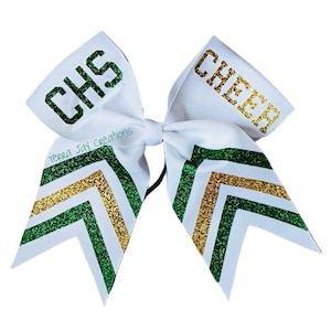 May include: White cheer bow with green and gold glitter chevron stripes. The bow has the text "CHS" on one side and "CHEER" on the other side.