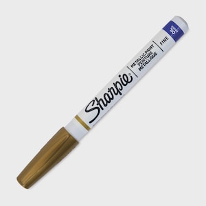 Könnte beinhalten: Ein goldfarbener Metallic-Paint-Sharpie-Marker mit feiner Spitze. Der weiße Schaft trägt das Sharpie-Logo und die Worte "METALLIC PAINT PEINTURE METALLIQUE" und "OIL BASED". Die Spitze ist goldfarben und das Ende ist blau.