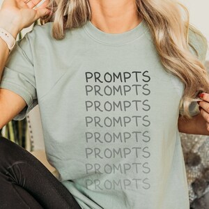 May include: A light green t-shirt with the word "prompts" repeated seven times in black text.