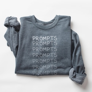 May include: A dark gray sweatshirt with the word "prompts" repeated six times in white text.