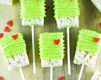 Könnte beinhalten: Grüne Rice Krispies Treats auf Stöcken mit roten Herzstreuseln. Die Leckereien sind in grüne Schokolade getaucht und haben rote Herzen oben drauf.