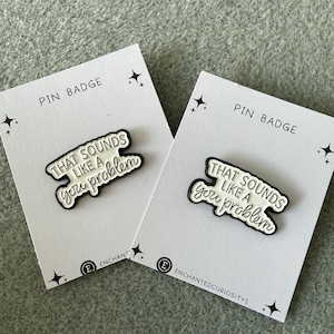 May include: Two pin badges on white cards. Each pin features the text "THAT SOUNDS LIKE A you problem" in black and white. The cards are labelled "PIN BADGE" and have a logo and text "ENCHANTEDCURIOSITYS".