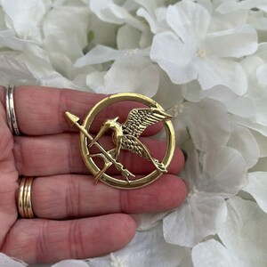 Hunger Games metal mockingjay/ mockingbird & arrow pin badge brooch presented in an organza gift bag Gold