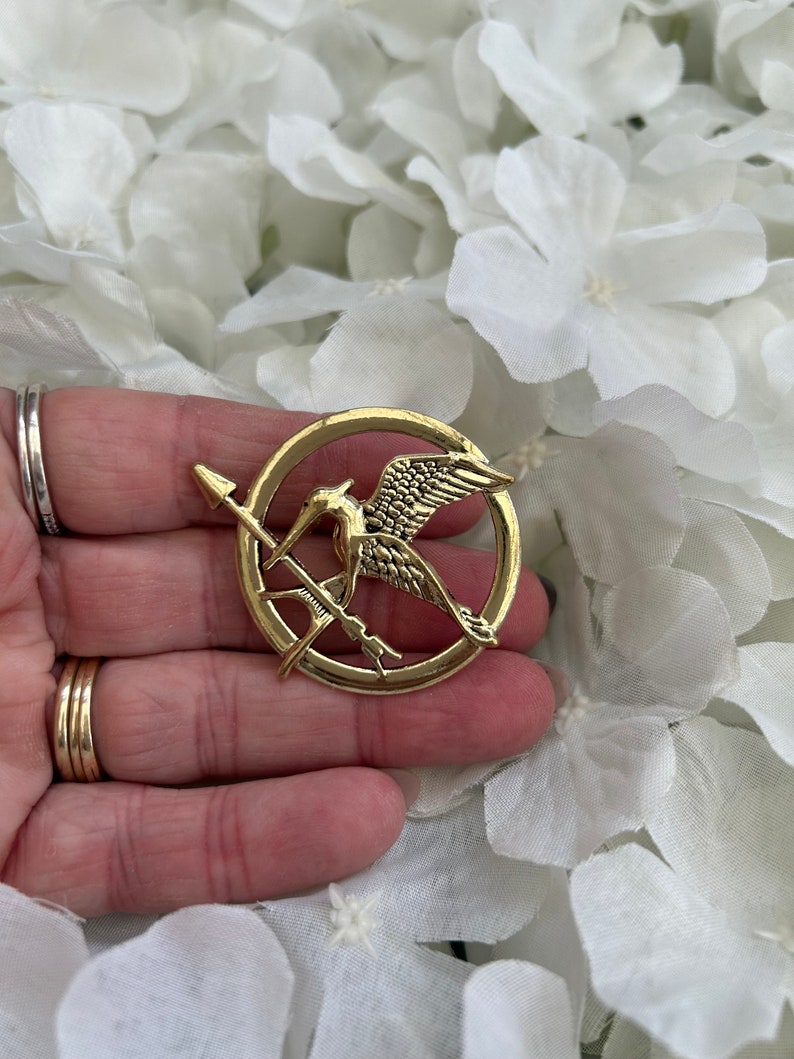Hunger Games metal mockingjay/ mockingbird & arrow pin badge brooch presented in an organza gift bag Gold