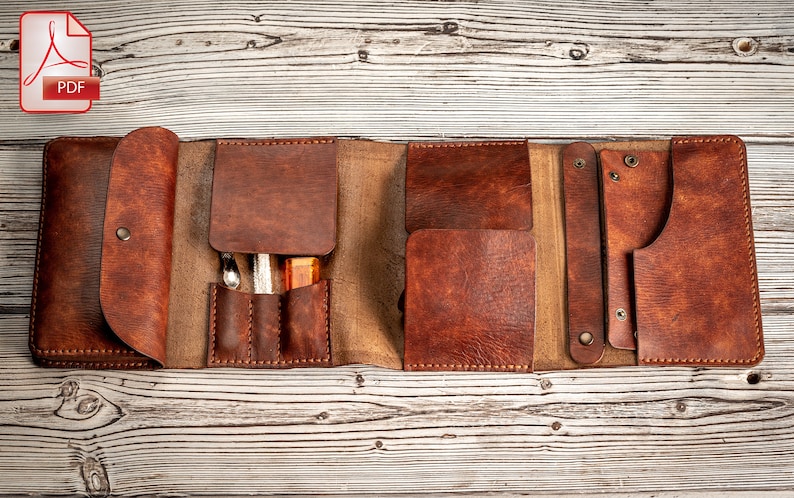 May include: A brown leather roll-up case with multiple pockets and slots for holding tools or supplies. The case is open and laid flat on a wooden surface.