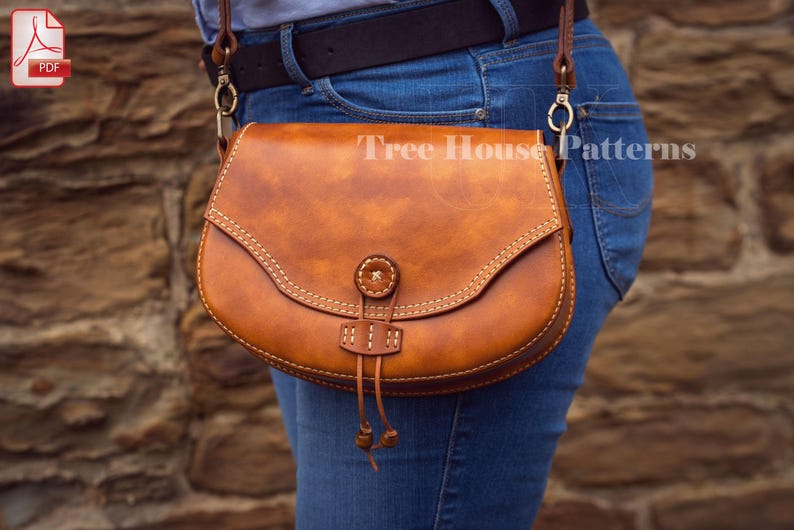 May include: A brown leather saddle bag with a flap closure and a decorative strap. The bag is worn over the shoulder and has a gold-toned buckle.