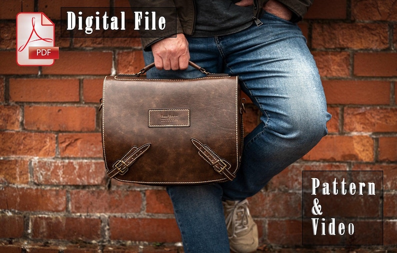 May include: A brown leather messenger bag with a strap and buckle closures. The bag has a label that says "The Mail Room" on it. The bag is being held by a person wearing blue jeans.