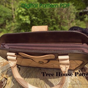 May include: A brown leather handbag with a zippered top and a light brown leather flap. The bag has a quilted design and a metal button closure. The bag is open and the inside is visible. The text "Tree House Patterns" is visible on the bottom of the image.
