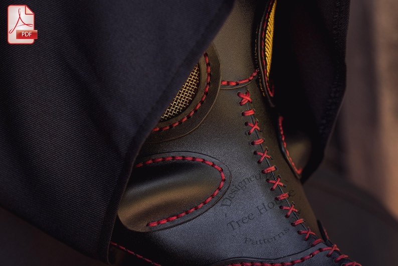 May include: A black leather mask with red stitching and a gold trim. The mask has a mesh covering the eyes and the text "Designed by Tree House Patterns" is embossed on the side.