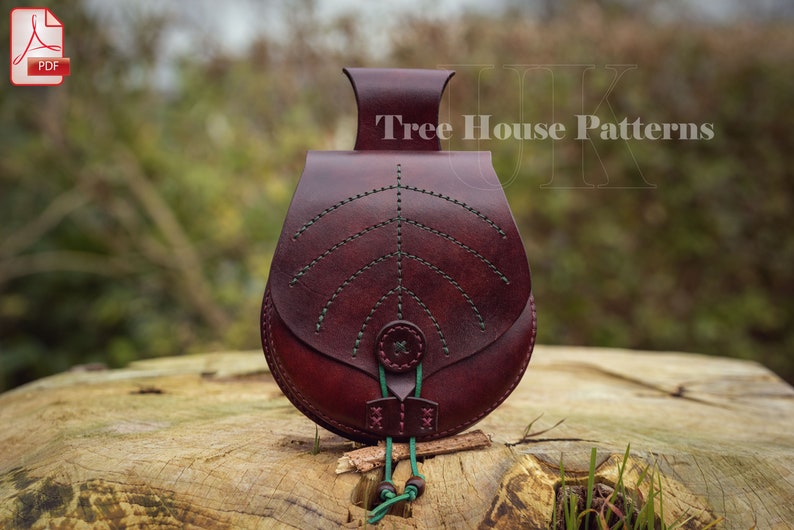 May include: A burgundy leather pouch with a green leaf design and a green drawstring. The pouch is sitting on a wooden surface. The text "Tree House Patterns" is visible in the background.