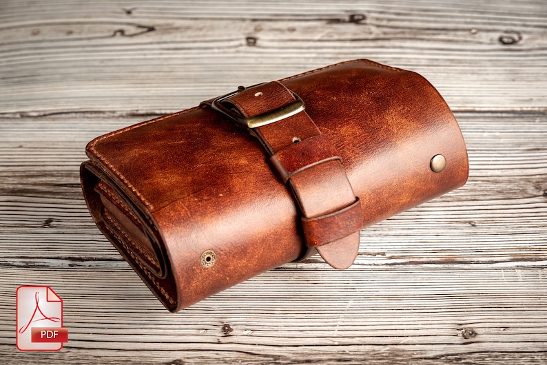 May include: A brown leather wallet with a buckle closure. The wallet is rolled up and has a distressed look.