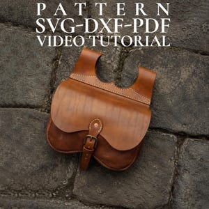 Op de afbeelding: Een handgemaakte bruin lederen tas met een gebogen flap en gespsluiting. De tas heeft een zadeltasontwerp met een handvat aan de bovenkant en decoratieve stiksels. De tekst "PATTERN SVG-DXF-PDF VIDEO TUTORIAL" is zichtbaar.