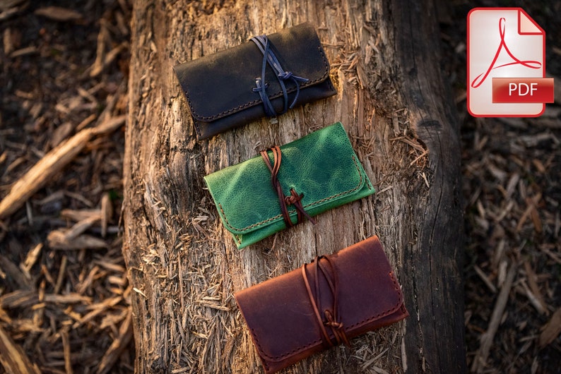 May include: Three leather pouches with different colored leather and tied with string. The pouches are on a wooden log.