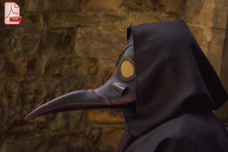 May include: A black leather plague doctor mask with a long, curved beak and a gold-colored eye piece. The mask is worn by a person in a black hooded robe.