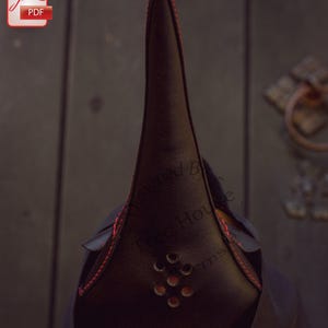May include: A black leather plague doctor mask with a long, pointed beak and red stitching. The mask has a series of small holes around the mouth area.