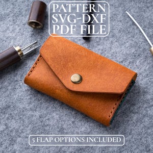 May include: A tan leather wallet with a flap and a brass button closure. The text "PATTERN SVG-DXF PDF FILE" is at the top, and "5 FLAP OPTIONS INCLUDED" is at the bottom. The wallet is on a grey surface.