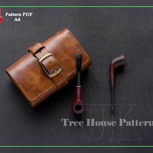 May include: A brown leather tobacco pouch with a brass buckle and stitching. The pouch is on a black surface with two wooden pipes.