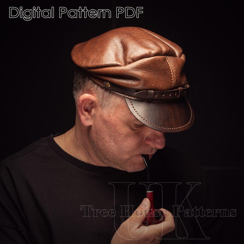 May include: A brown leather cap with a strap and buckle. The cap has a slightly rounded crown and a wide brim. The cap is being worn by a person holding a pipe.