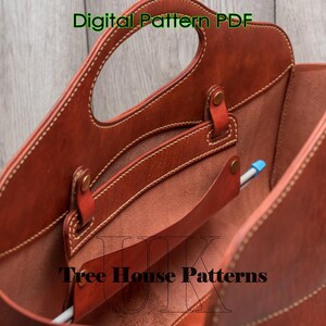 May include: A brown leather tote bag with a top handle and a zipped pocket. The bag is open and the inside is visible. The bag is labelled "Tree House Patterns".