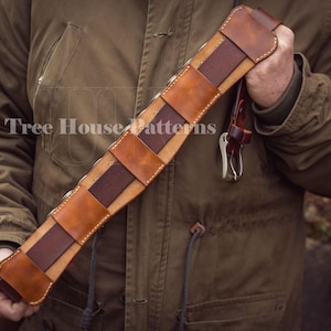May include: A brown leather belt with a dark brown leather insert. The belt is made of multiple pieces of leather that are stitched together. The belt is designed to hold multiple cartridges.