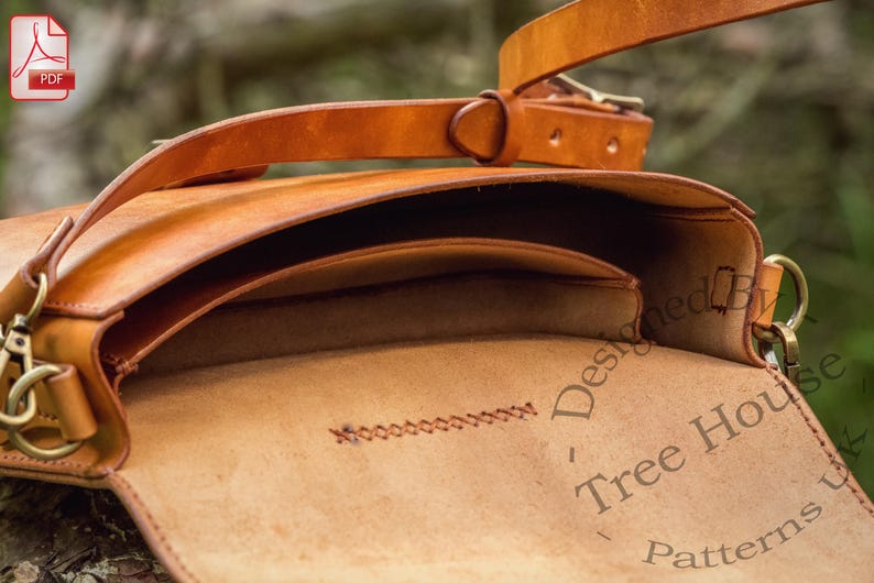 Puede incluir: Un bolso de cuero marr&oacute;n con cierre de solapa y una correa larga. El bolso est&aacute; abierto y el interior est&aacute; forrado con tela marr&oacute;n. El bolso est&aacute; dise&ntilde;ado por Tree House Patterns.