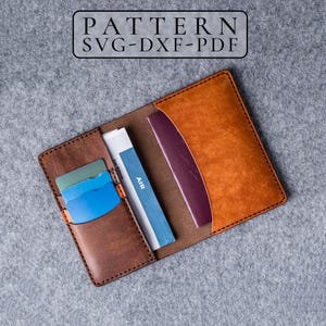 May include: A brown leather passport holder with black stitching, featuring a pocket for cards and a slot for a passport. The text PATTERN SVG-DXF-PDF is visible at the top. The holder contains a blue card, a green card, and a blue document.
