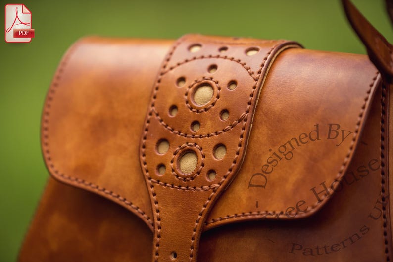 Puede incluir: Un bolso de cuero marr&oacute;n con una solapa decorativa que presenta un patr&oacute;n circular y costuras. El bolso est&aacute; estampado con el texto "Designed By...Free House Patterns".