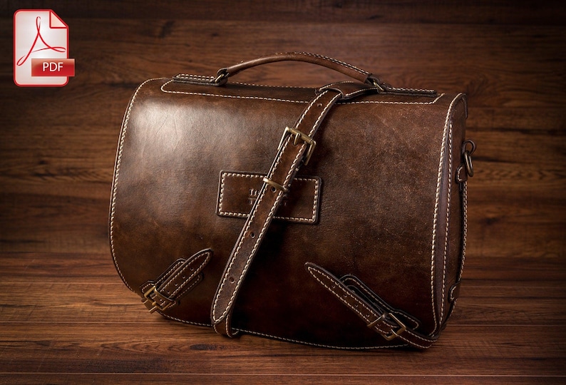 May include: A brown leather briefcase with a long strap and a buckle closure. The bag has a stitched design and a flap with a metal clasp.