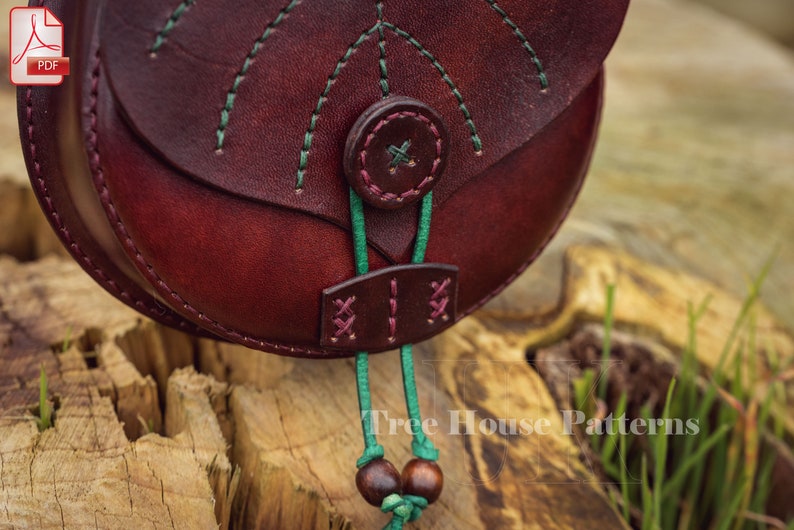 May include: A close-up of a burgundy leather bag with green stitching and a green cord with wooden beads. The bag has a flap with a button closure and a decorative design on the front. The text "Tree House Patterns" is visible in the bottom right corner of the image.