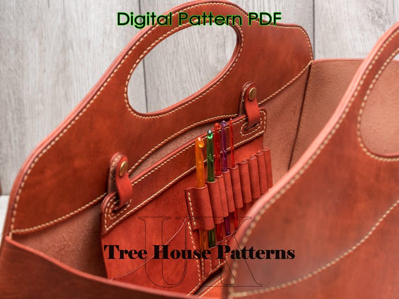 May include: A brown leather tote bag with a top handle and multiple pockets inside. The bag is open and you can see the interior pockets. The text "Tree House Patterns" is visible on the bottom of the bag.