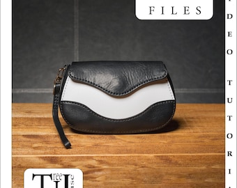 Può includere: Una borsa a mano in pelle nera e bianca con una patta curva. La borsa ha una cerniera dorata e una tracolla. La borsa è appoggiata su una superficie di legno. PDF FILES è scritto in nero su sfondo bianco.