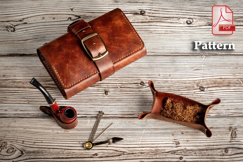 May include: A brown leather tobacco pouch with a buckle closure, a red pipe, a small metal tool, and a brown leather tobacco tray filled with tobacco.