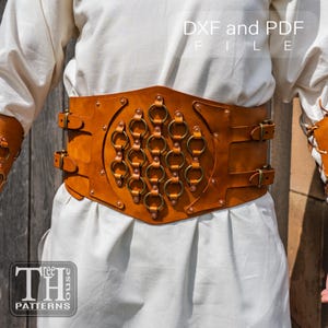 Pode incluir: Um cinto largo de couro castanho com vários anéis e fivelas de latão. O cinto tem um design decorativo com rebites e está rotulado como "DXF and PDF FILE". O logotipo "Three House Patterns" é visível na parte inferior.