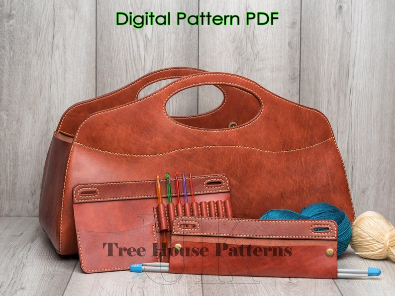May include: A brown leather knitting bag with a zipped pocket and a separate needle holder. The bag has a handle and is labelled "Tree House Patterns".