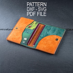 Può includere: Portafoglio in pelle aperto con pannelli arancioni e verde acqua, contenente una carta di credito e un passaporto. Il portafoglio è assicurato con una chiusura a scatto. Il testo "PATTERN DXF - SVG PDF FILE" è visualizzato in alto.